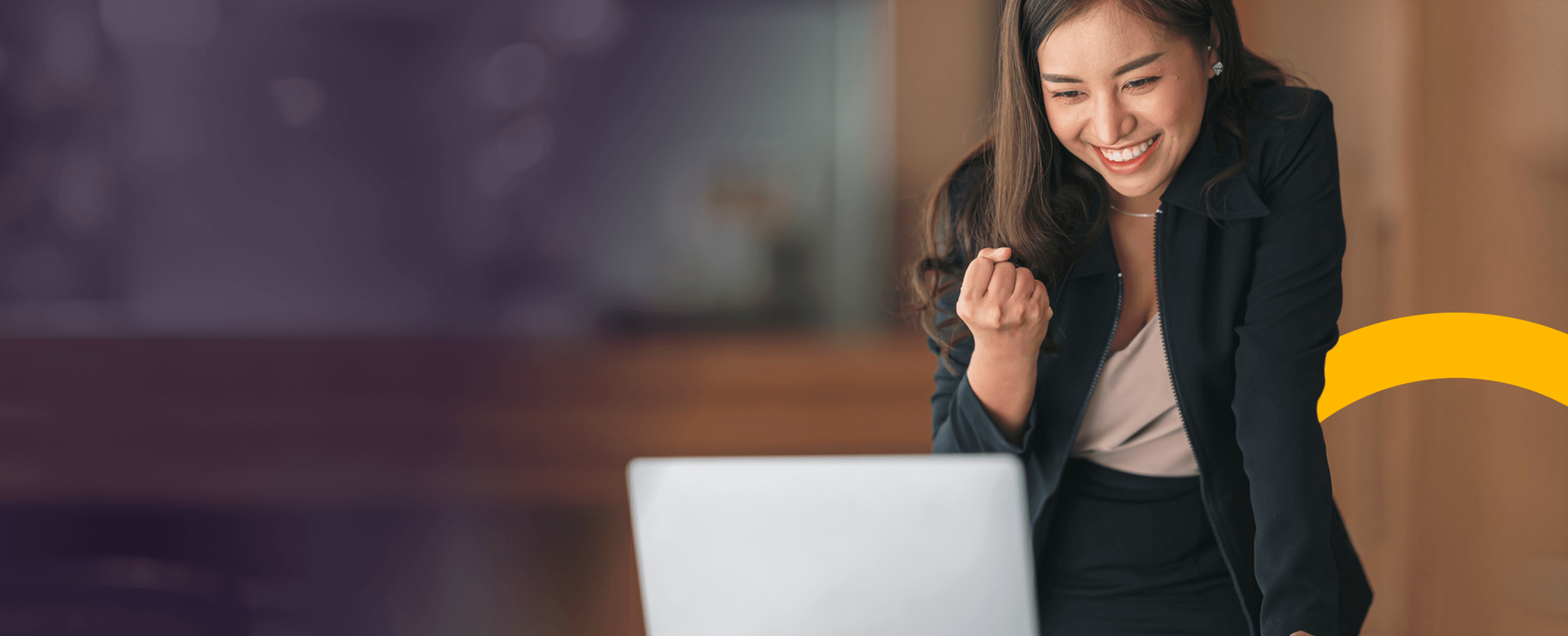 Woman celebrating as she looks at laptop